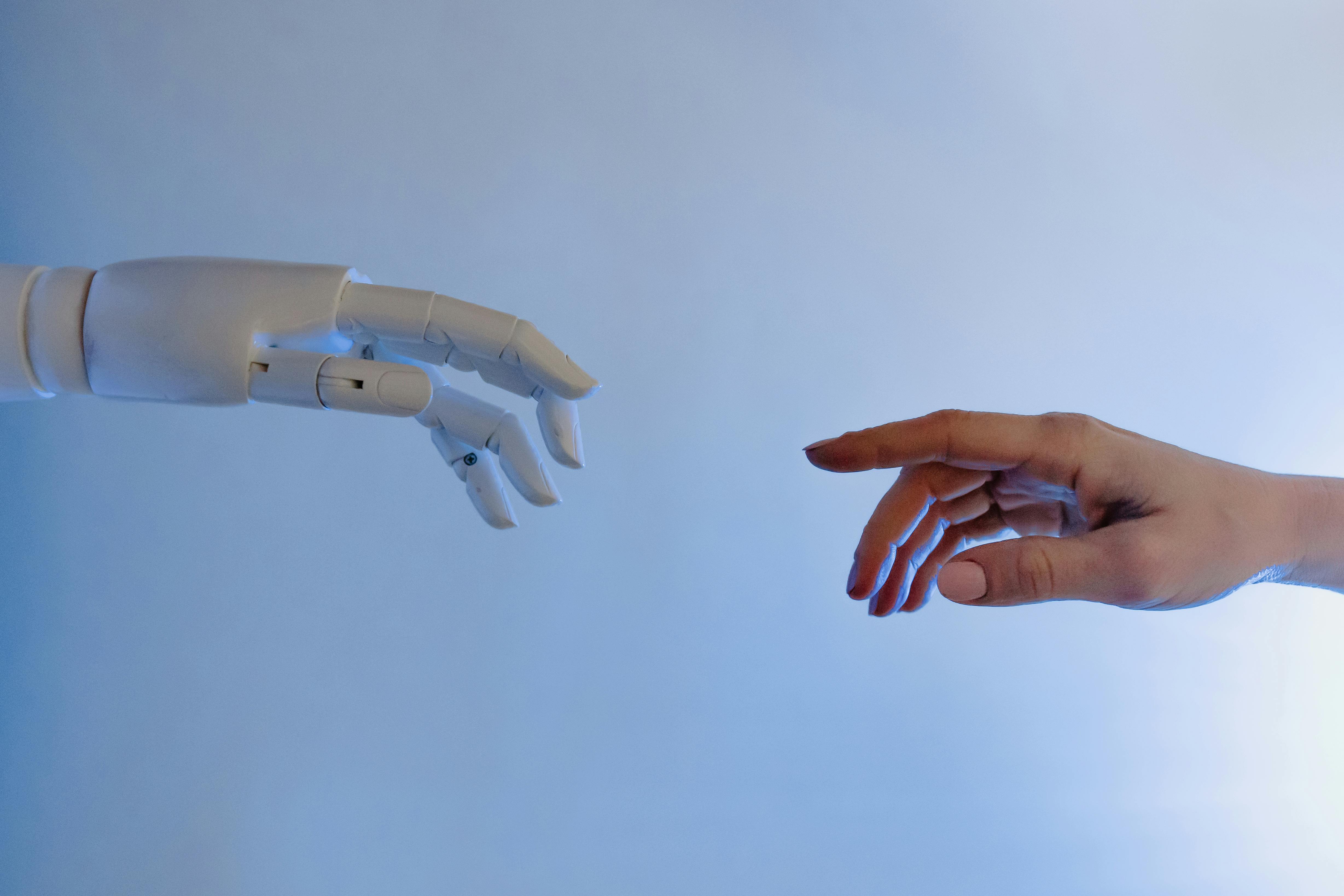 human hand and robot hand reach out to eachother